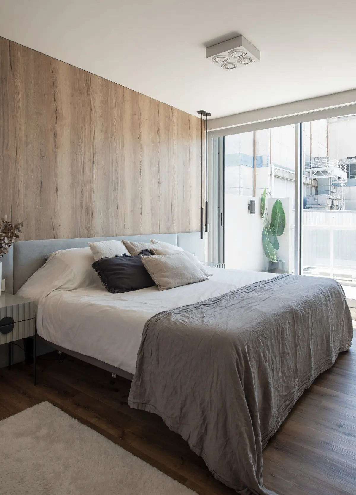Dormitorio moderno con pared de madera, cama king y luz indirecta — proyecto Depto Arribeños, por Ayelen Mayer Arquitectura, en Buenos Aires
